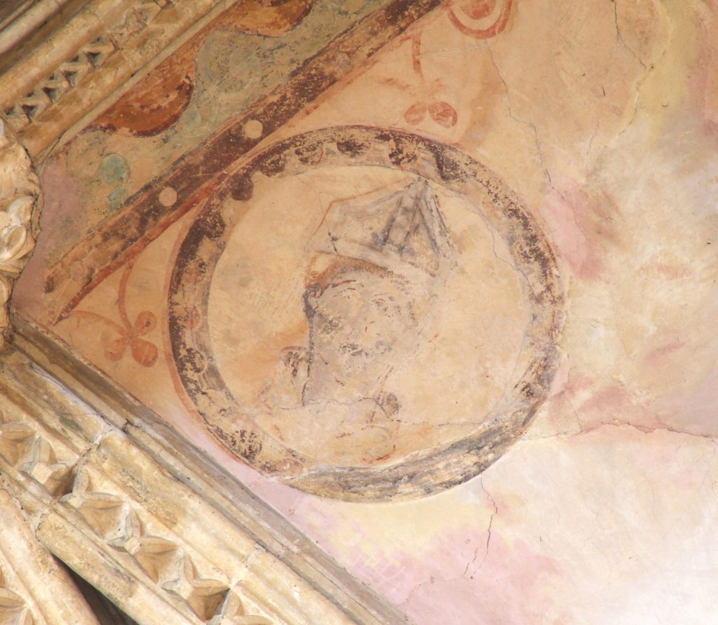 Image of painting of a bishop's head surrounded by a roundel in the south arm of the Great Transept at Lincoln Cathedral