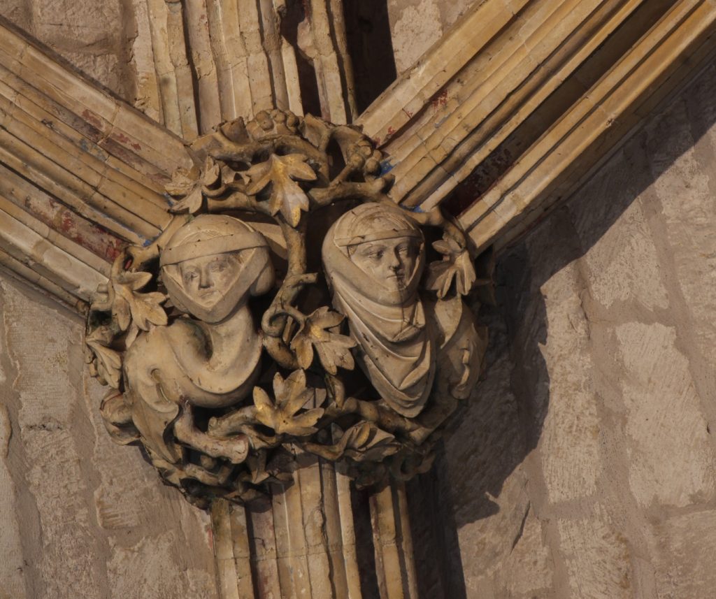 Image of boss in the Angel Choir aisle at Lincoln Cathedral, showing two serpentine creatures with long curving necks and the faces of women wearing wimples