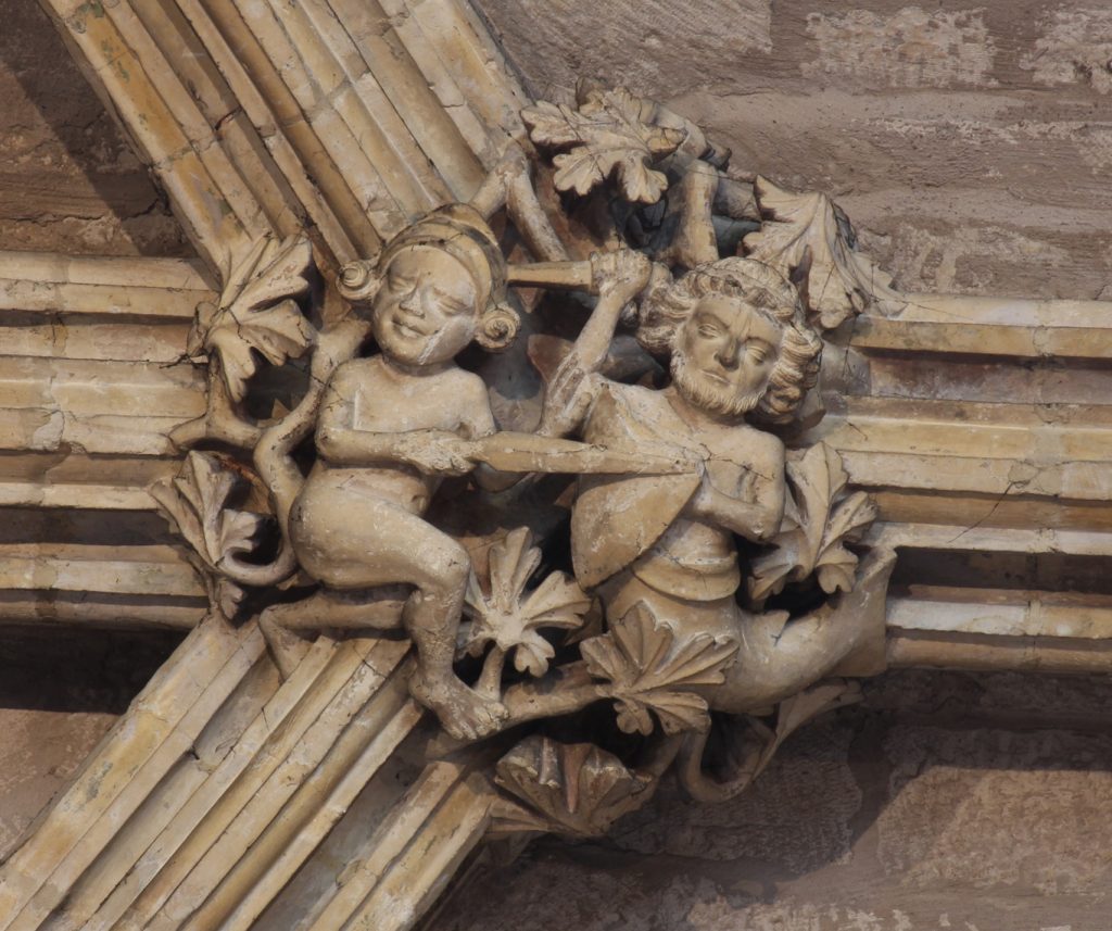 Image of boss in the Angel Choir aisle at Lincoln Cathedral, showing a fight between an armed naked man and a merman defending with sword and shield