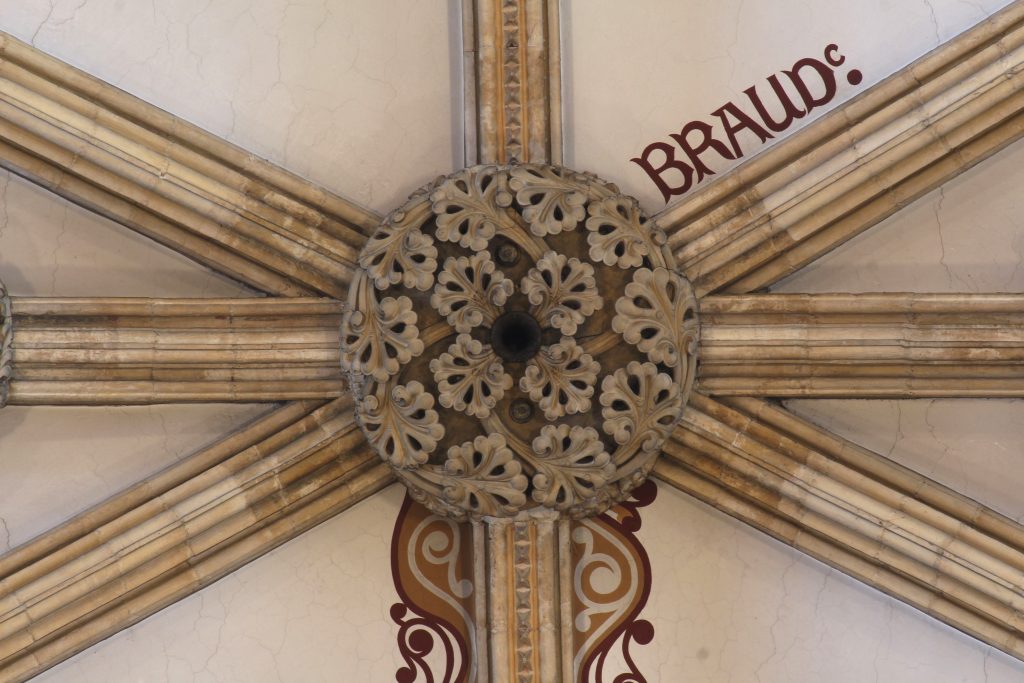 Image of central boss in the nave vault at Lincoln Cathedral, showing the name 'Braud'' painted on the adjacent webbing and painted scrollwork flanking the rib